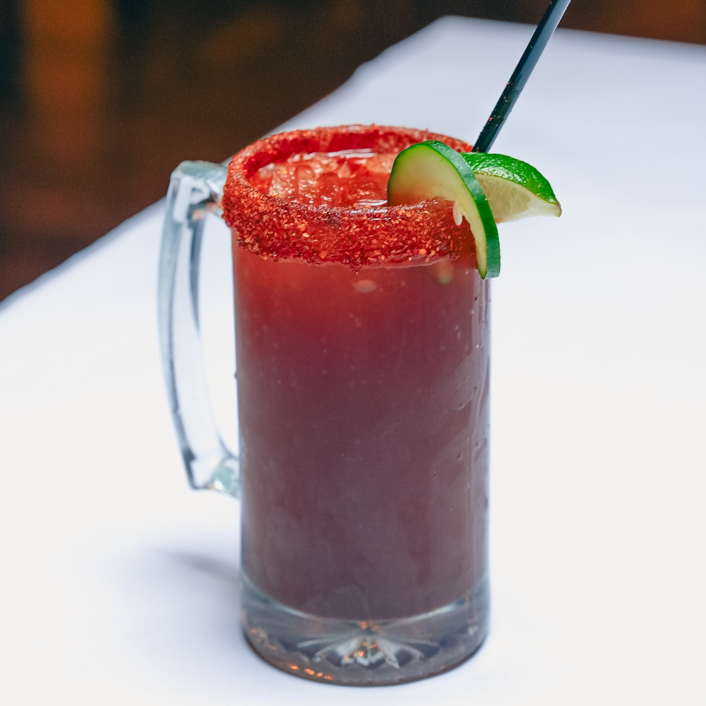 The house michelada served with a tajin rim, cucumber and lime